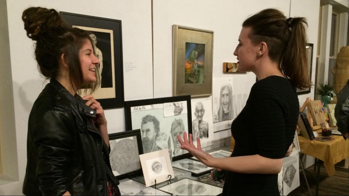 Appleton-based CSA artist Ali Fuller (right) chats with a shareholder near a display  of her drawings.