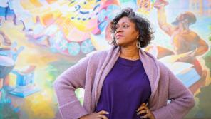 Wisconsin Poet Laureate Dasha Kelly Hamilton stands in front of The Rebirthing of the Earth Mother, a mural artist Tia Richardson created in 2018 for an exterior wall of the Historic Garfield Apartments (originally Garfield Street School) in Milwaukee’s Bronzeville neighborhood. Photo by TJ Lambert/Stages Photography