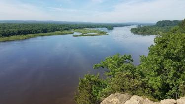 The view down the Wisconsin River from Cactus Bluff in Ferry Bluff State Natural Area. Millions of years ago this valley was carved to a depth of over 600 feet by an ancient river. The last major glaciation deposited as much as 300 feet of sand and gravel, resulting in the broad floodplain and terraces that characterize the Lower Wisconsin River valley today. Photo by Eric Carson.