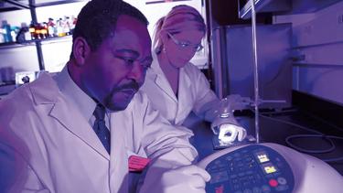 Chukuka S. Enwemeka, dean of UWM’s College of Health Sciences, conducts an experiment with research associate Violet Bumah. Among Enwemeka’s discoveries in phototherapy research: blue light in a certain wavelength kills the antibiotic-resistant “superbug” form of Staphylococcus aureus.